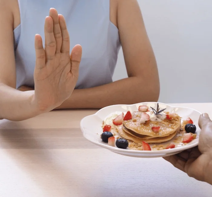 Woman refusing a plate of pancakes
